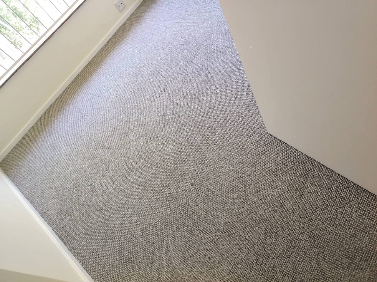 Freshly cleaned grey carpet beside a window